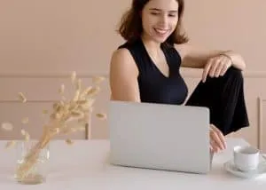 Smiling woman working confidently on a laptop, symbolising focus, motivation, and personal growth through mindset coaching.